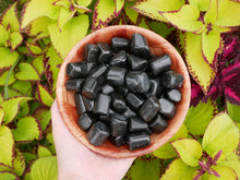 Load image into Gallery viewer, Black tourmaline tumbled stones in a wooden colored bowl
