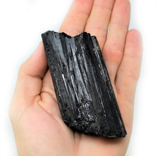 Load image into Gallery viewer, Black Tourmaline with biotite mica mix rough stone on a human&#39;s hand
