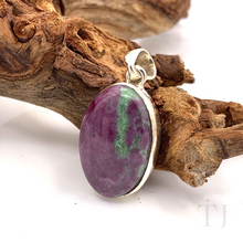 Load image into Gallery viewer, Anyolite Ruby in Zoisite Oval Cabochon Silver pendant is lying on a branch
