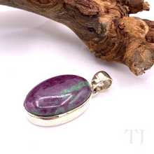 Load image into Gallery viewer, Anyolite Ruby in Zoisite Oval Cabochon Silver pendant lying beside a branch
